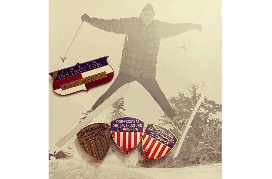 A collection of PSIA-AASI pins and Walt Weber's vintage name badge sitting on a historic ski photo of him.