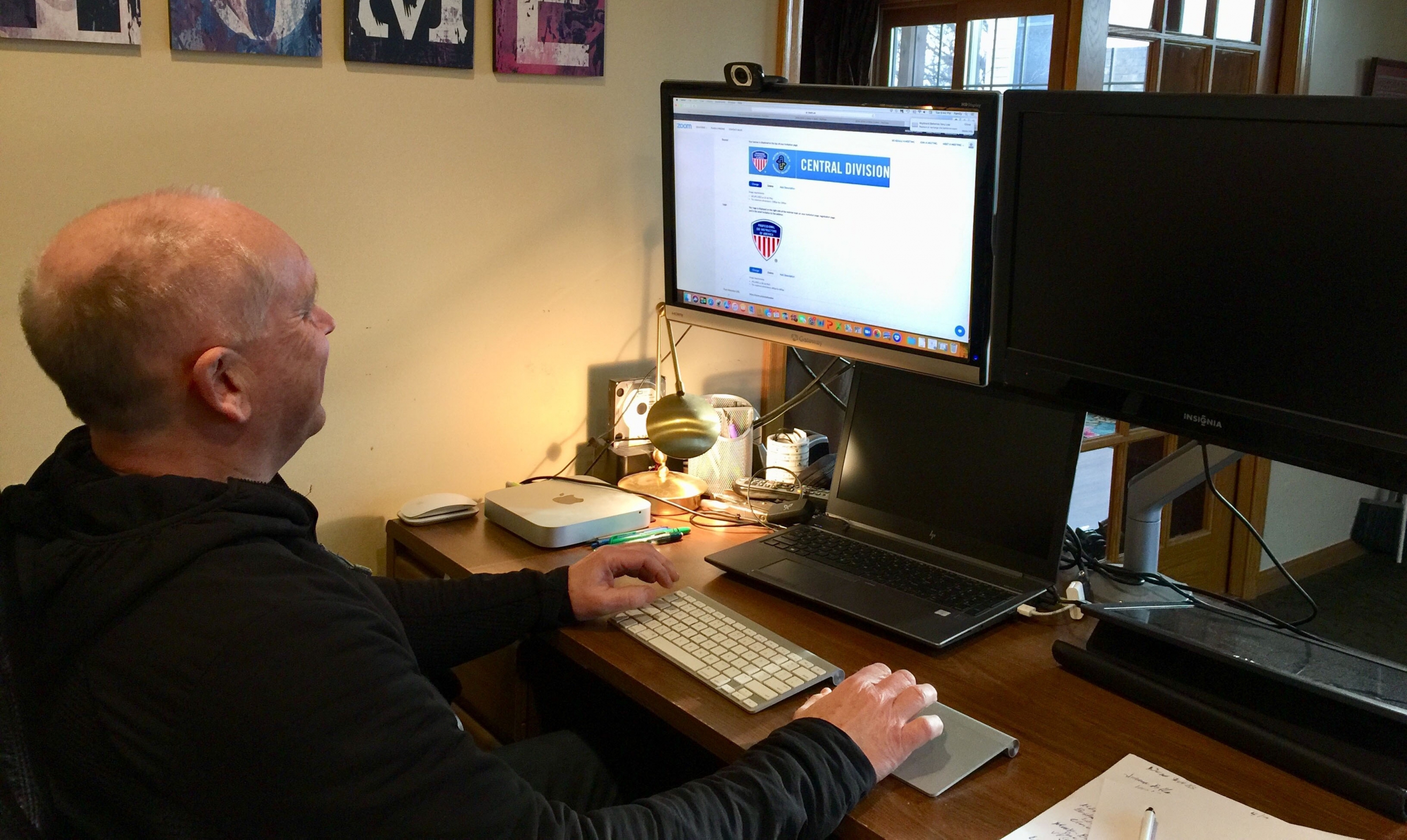 A man sits at a desktop computer taking a PSIA-AASI webinar