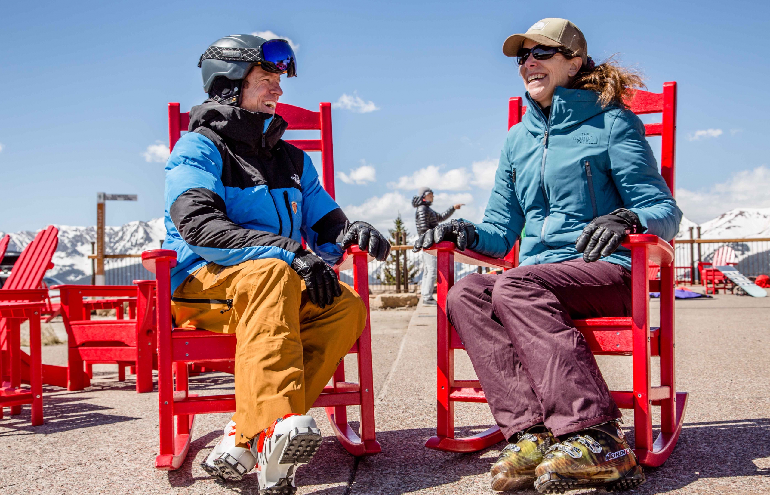 PSIA-AASI ski instructors talk while sitting in red chairs.