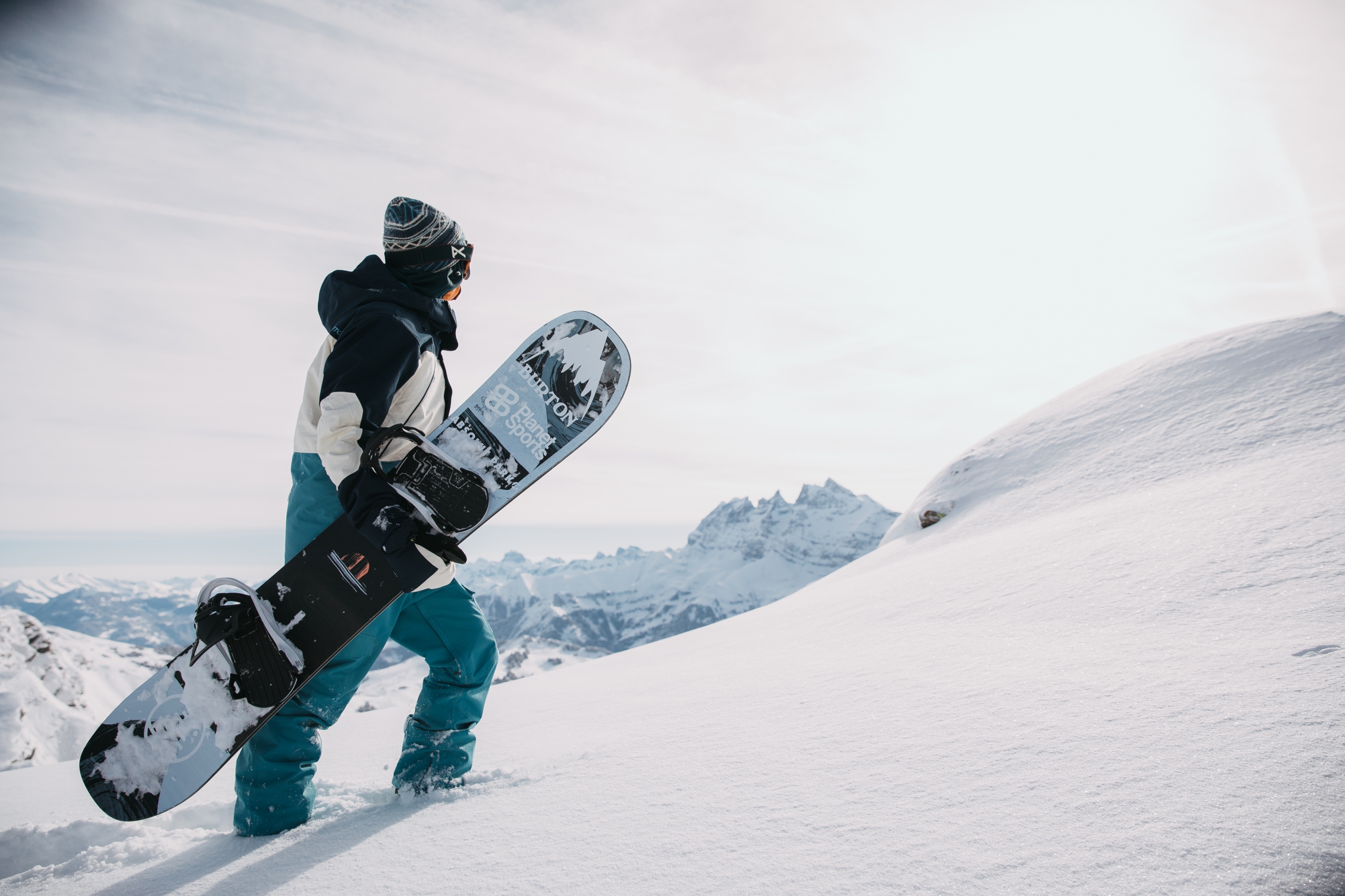 A snowboarder holds their board and walks up a slope