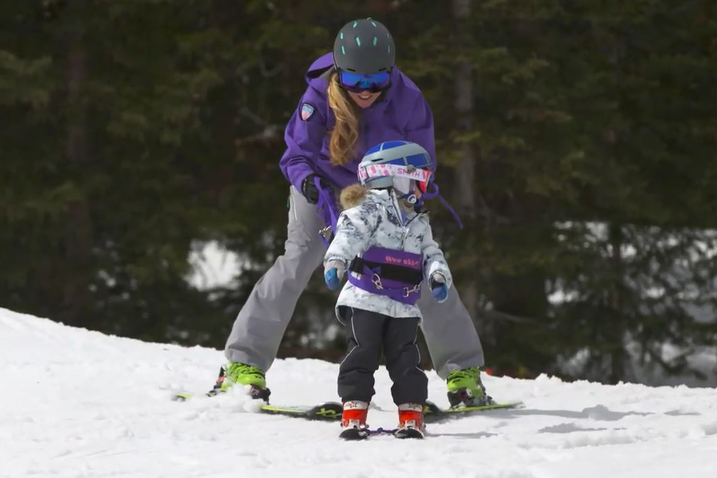 A mom teachers her kids to ski.