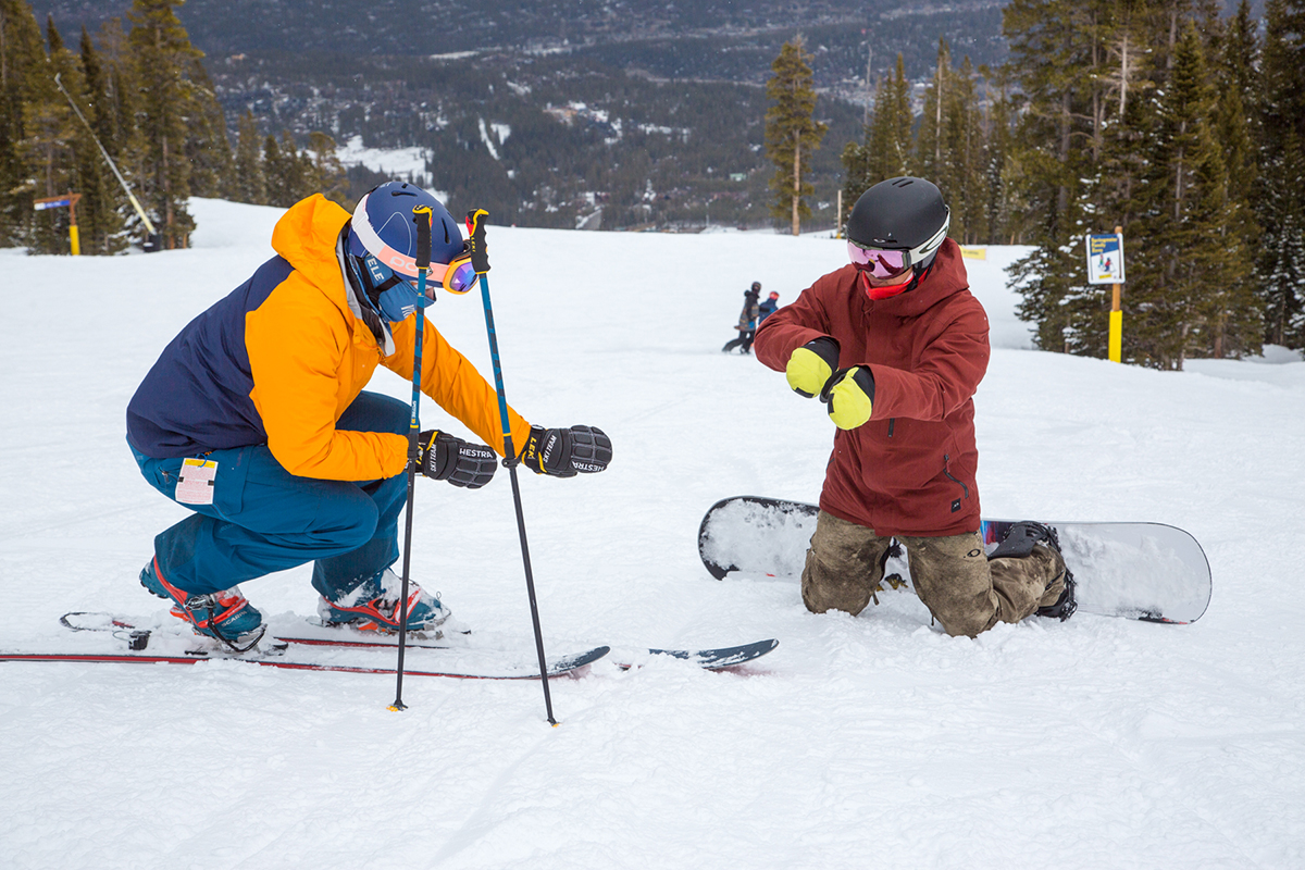 A telemark skier and snowboarder use their hands to show body position and movement on the snow